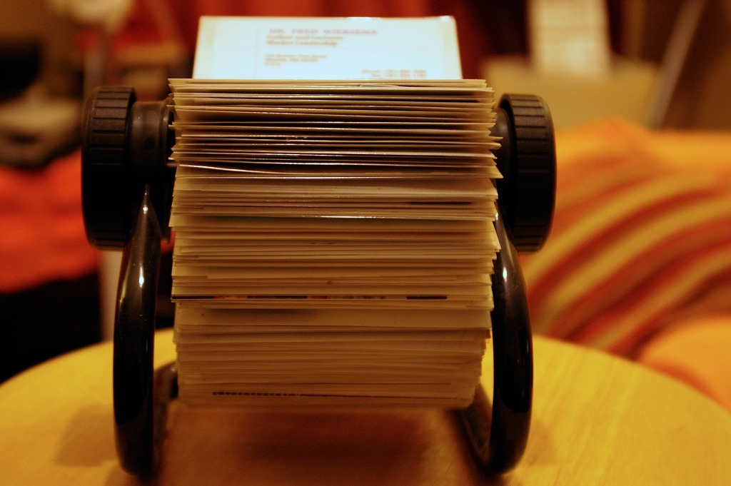 a Rolodex filled with several hundred different pieces of paper sits on a desk.