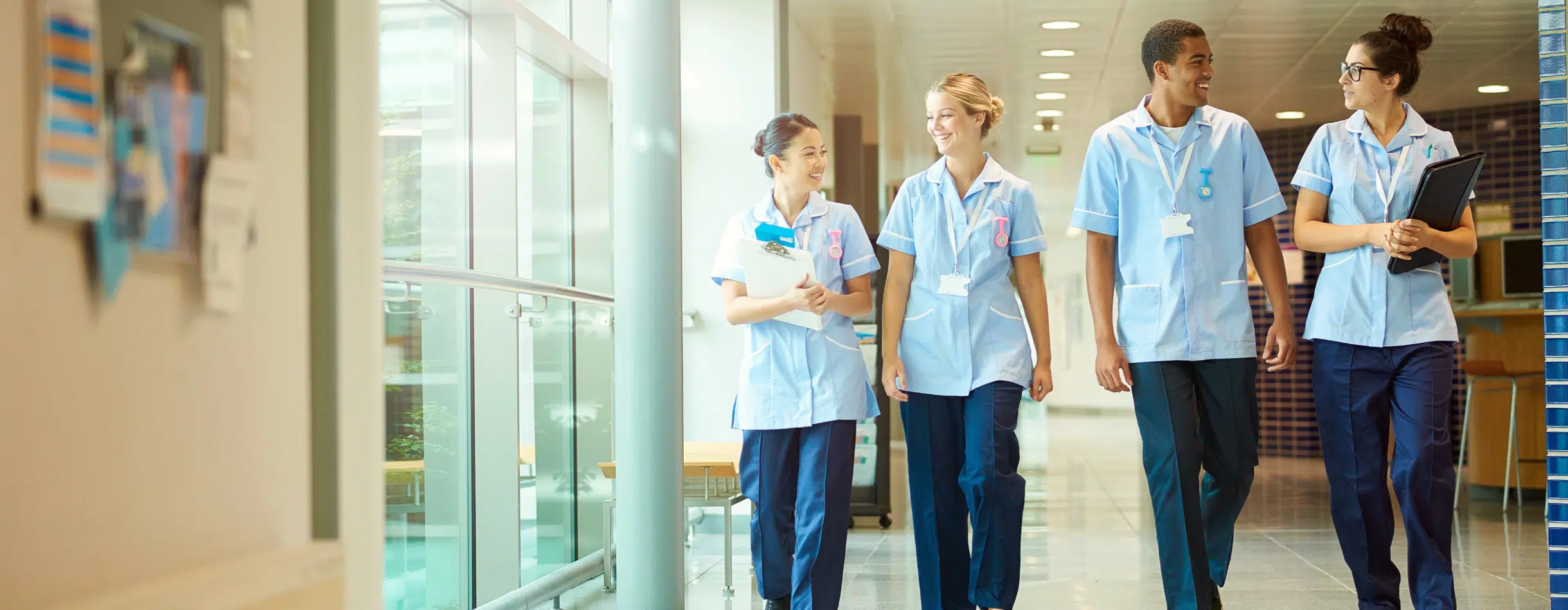 A group of healthcare professionals walk through a hallway, making small talk with one another.