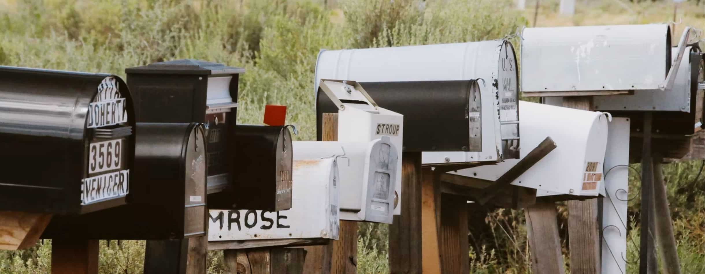 Several mailboxes all lined up next to a road.