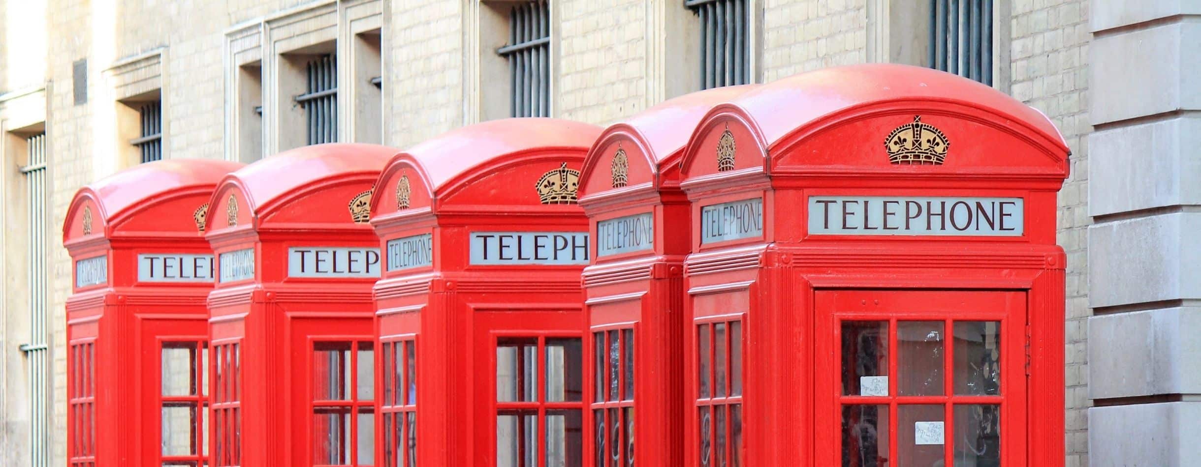 Four Red Telephone Booths on the street with Telephone written across the top of each.