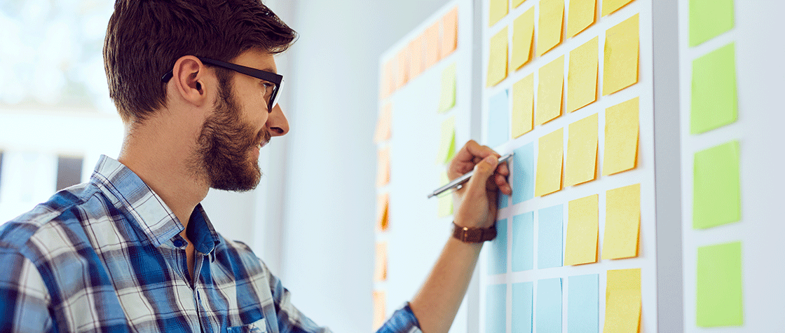 man planning on post-it note wall