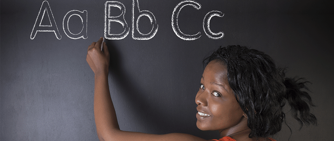 woman writing ABCs on chalkboard