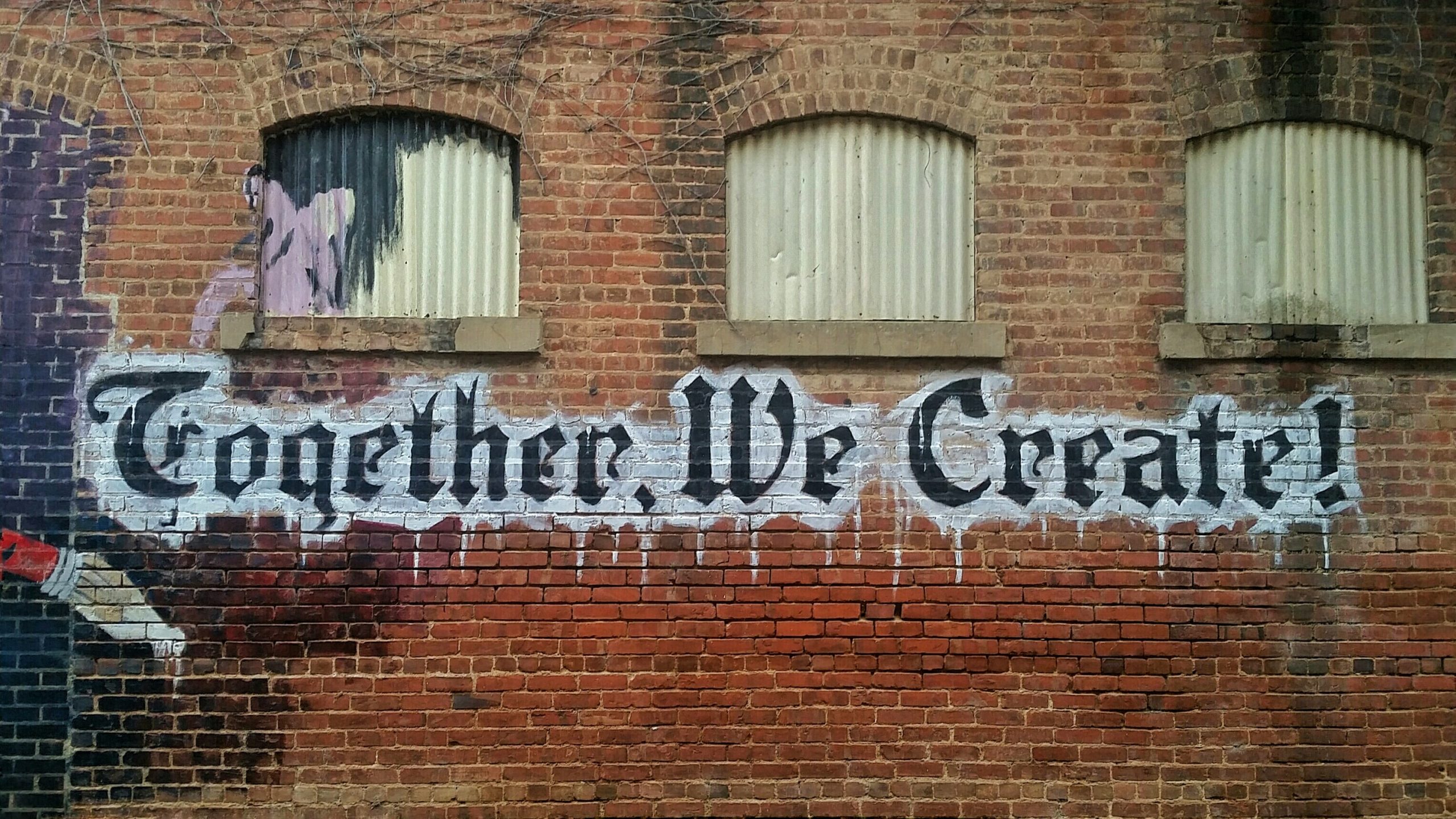 "Together We Create" painted on a brick wall