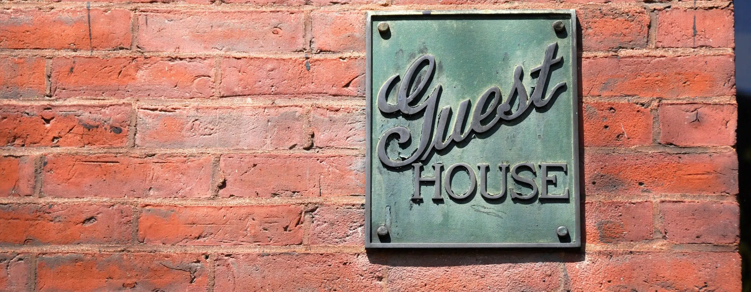Guest House sign on brick wall.