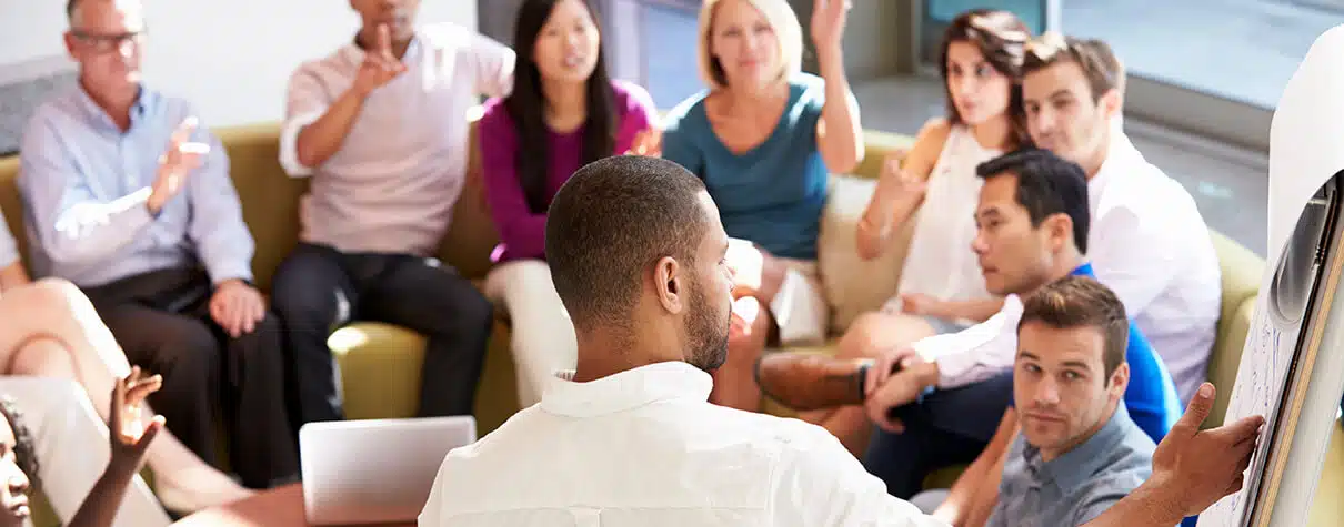 This image shows a group of people sitting in on a couch having a meeting.
