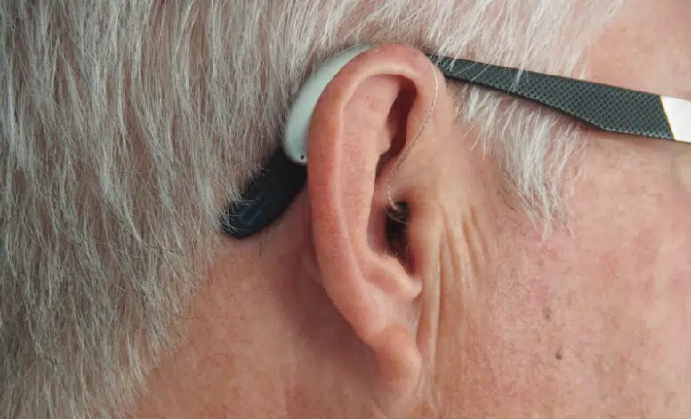 A man’s ear with a hearing aid attached