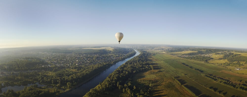A hot air balloon soars above a river, representing a unique live auction item