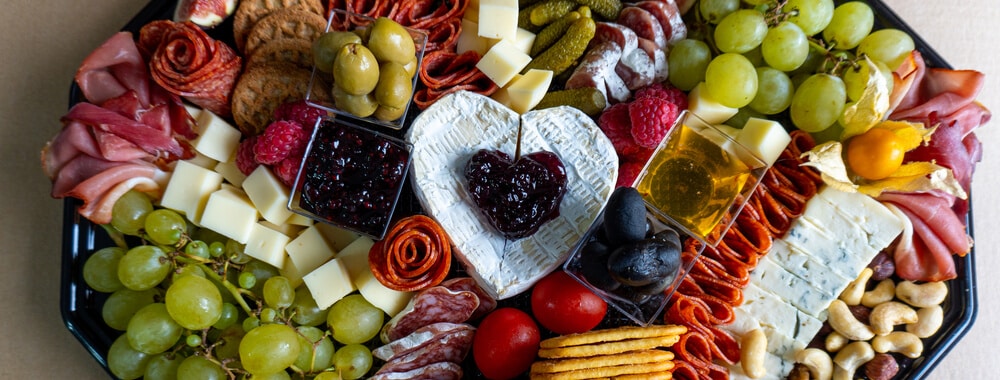 A charcuterie board with meats, cheeses, crackers, grapes, and more, representing a food-themed auction prize